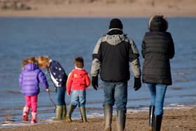 Family playing at the seaside in winter, Instow, Devon, UK. (Photo by: Education Images/Universal Images Group via Getty Images)